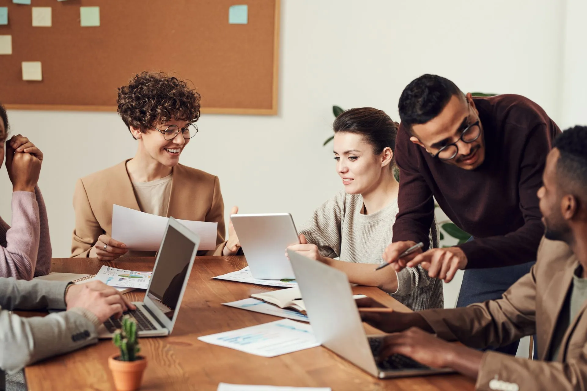 A team gathered around laptops at a meeting table, talking through their work